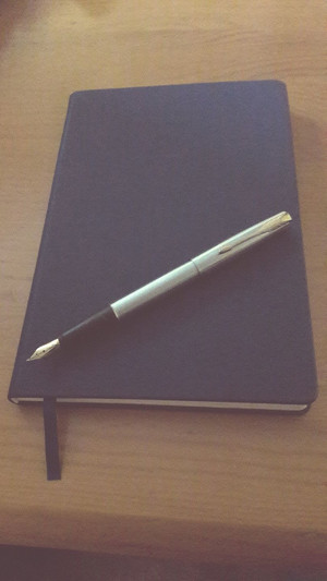 Closed notebook and fountain pen